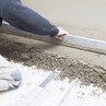 Levelling concrete floor with a straightedge by hand