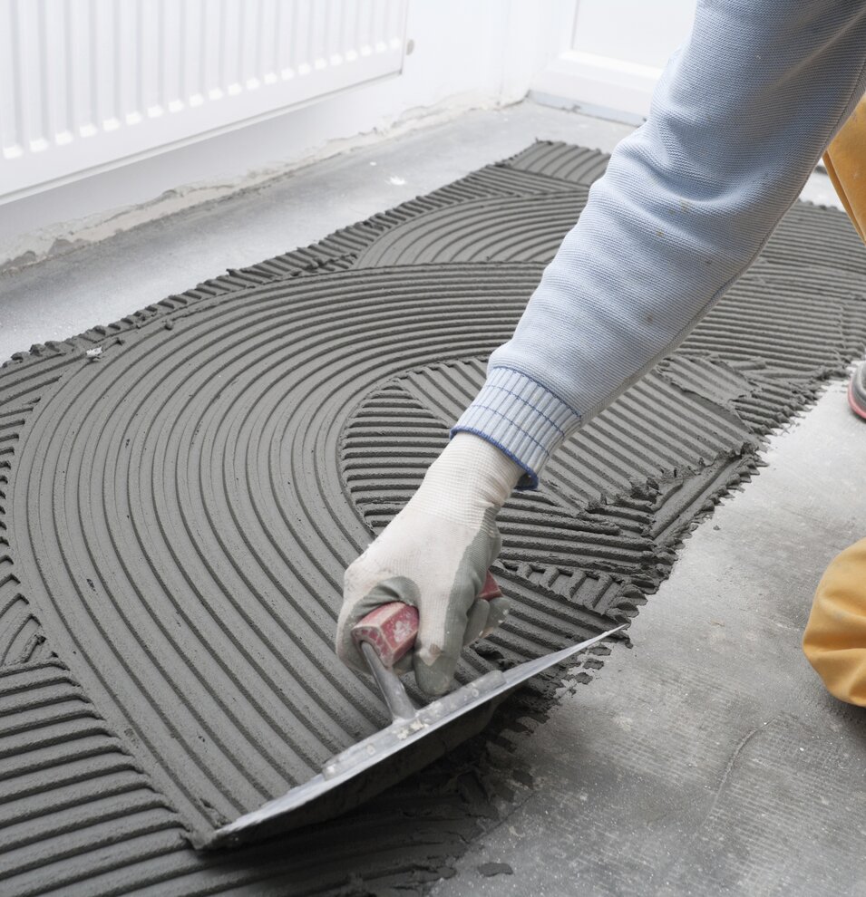 Tile adhesive is spread on the floor with notched trowel