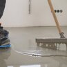 Spreading floor leveling compound on the floor with squeegee
